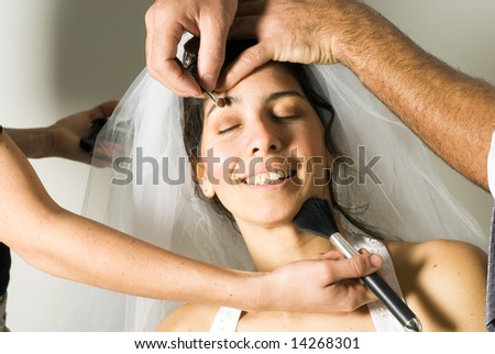 A woman smiling, while getting her make-up done. - horizontally framed