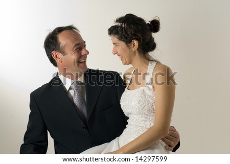 A newly married couple, smile at each other, wife sits on husbands lap. - horizontally framed