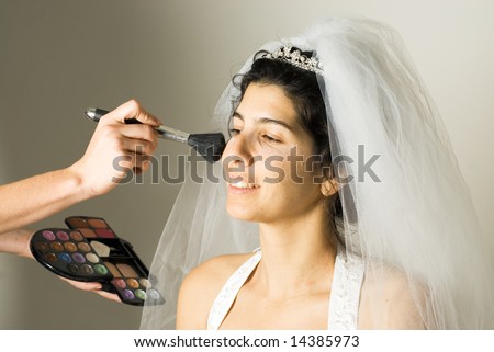 Makeup Artist applying makeup to a beautiful bride.  Horizontally framed shot.