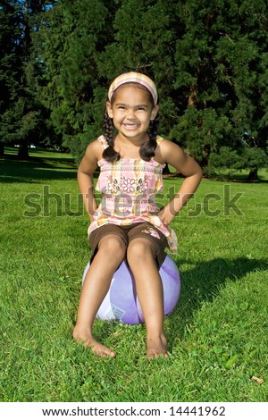 Happy little girl on a bouncy ball - Vertically framed photograph.