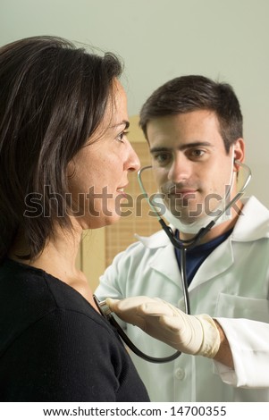 A male doctor checking the pulse on a female patient, sitting tall, using a stethoscope. - vertically framed