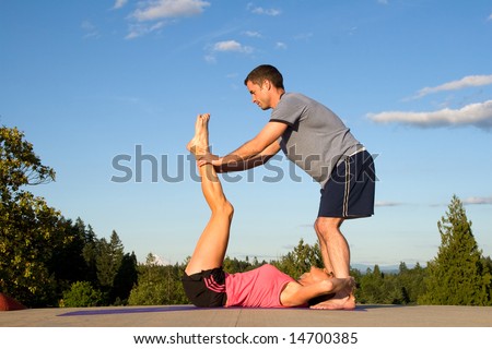 A woman, works her abs out by having a man stand above her, pushing her legs out. - horizontally framed