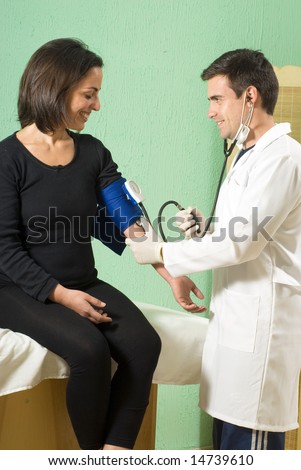 A young doctor, standing, checking his patient\'s blood pressure. - vertically framed