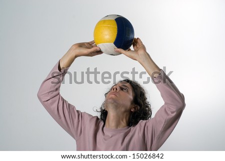 A man, standing, acts as if he were to set a volleyball up. Horizontally framed shot.