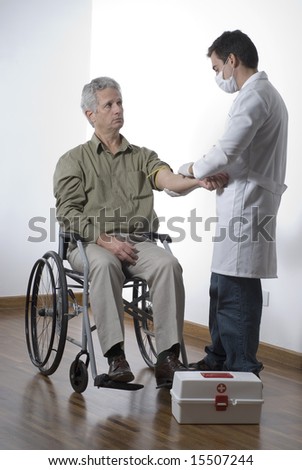 A patient is sitting in a wheelchair at a doctors office.  The doctor is bandaging his arm.  The doctor is looking at the patient and the patient is at the doctor.  Vertically framed shot.