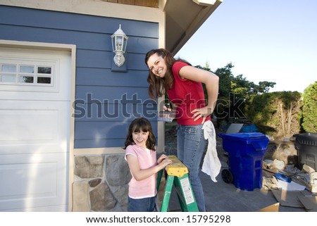 Mom and daughter being silly with paint on their faces. The mother is standing on a ladder. Horizontally framed photograph