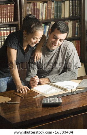 Couple studies in library. There are books and tools on the table and they are leaning against each other. Vertically framed photo.