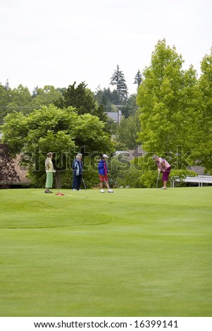 Group of four women playing golf. Vertically framed photo.