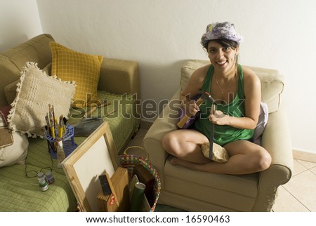 Female artist chiseling a rock and smiling in an easy chair. Horizontally framed photo.