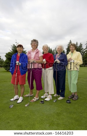 Five smiling, elderly women carrying golf clubs. Vertically framed photo.