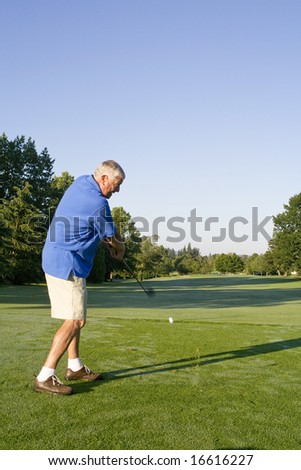 Man playing golf swings his golf club. Vertically framed photo.