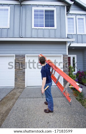 Man standing in front of house holding ladder and hammer. Vertically framed photo.