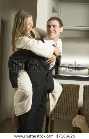 Couple smiling at each other as the man gives the woman a piggyback ride. Vertically framed photo.