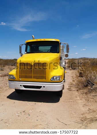 Photo of grille of yellow truck while working at a construction site. Vertically framed photo.