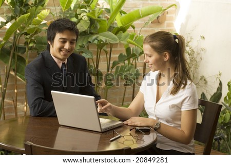 Smiling man and woman at a desk with a laptop computer. Horizontally framed photo.