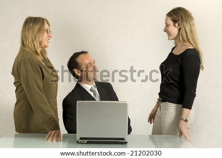 A man and two women in an office setting.  They are smiling and facing one another. Horizontally framed shot.