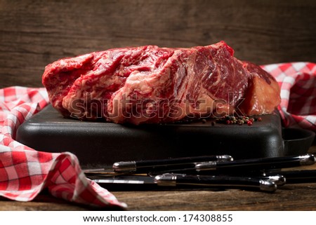 Raw rib eye, pepper and steak knives