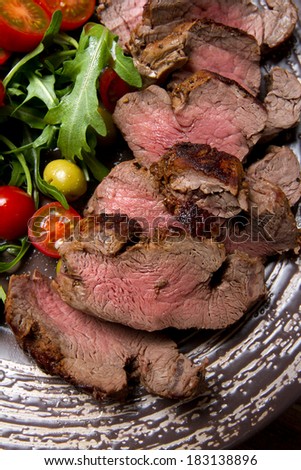 Grilled beef tenderloin with cherry tomatoes and arugula on a plate