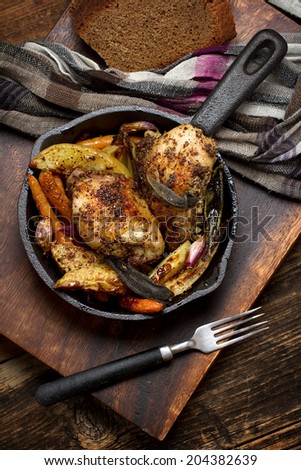 Rural chicken baked with potatoes, carrots, garlic and sage in cast iron skillet
