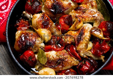 Roasted chicken with garlic, tomatoes and spices in a cast iron skillet