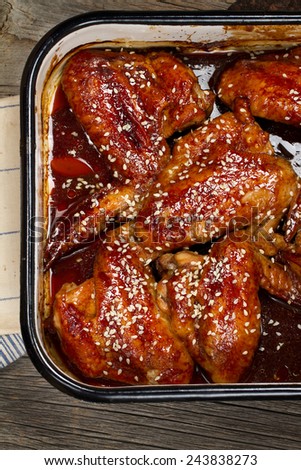 Soy sauce and honey glazed chicken wings with sesame seeds in metallic form