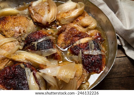 Braised chicken with onions and wine in a copper pan