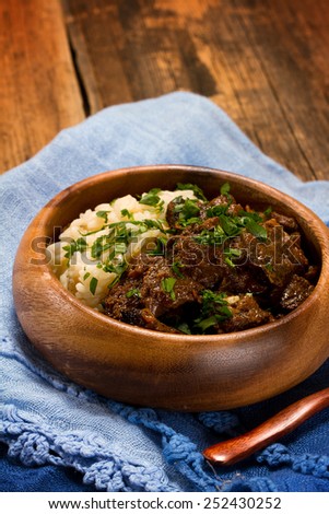 Slow cooked spicy beef curry with rice in a wooden bowl