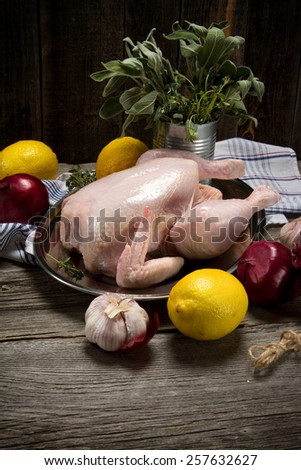 Raw chicken, lemons, onions, garlic, thyme and sage in a rustic style