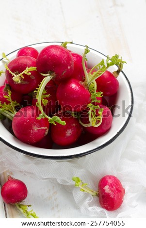 Red raw radishes in an old white bowl