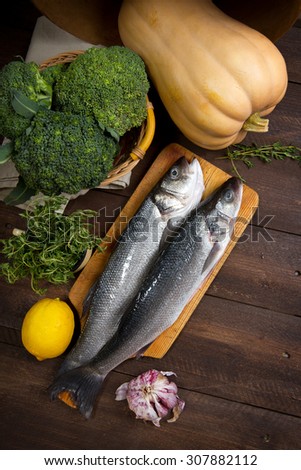 Raw sea bass, pumpkin, broccoli, lemon, thyme and garlic on a table