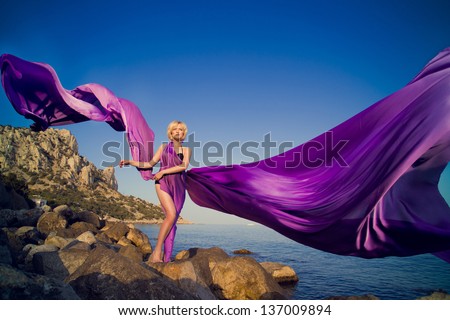 Beautiful girl standing on a rock near the water