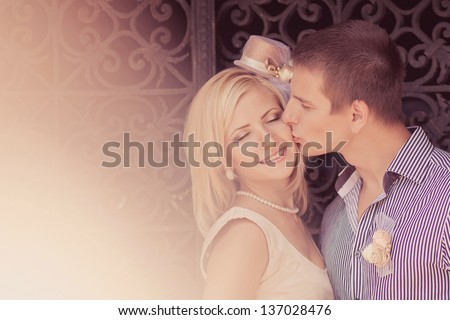Photo of wedding kissing pair against gate