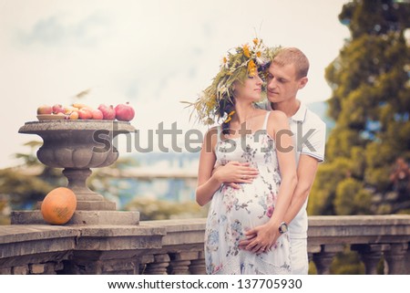 Portrait of a couple in love during pregnancy in the park with fruit and melon