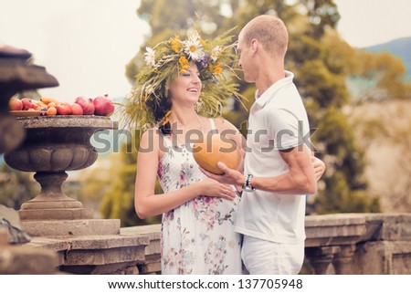 Portrait of a couple in love during pregnancy in the park with fruits and melon in the hands of
