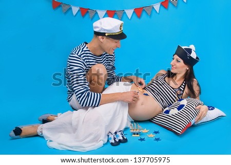 Studio portrait of a happy couple during pregnancy in a marine style