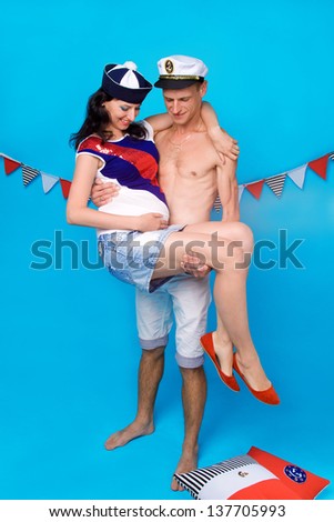Studio portrait of couple in love during pregnancy in a marine style, with cushions