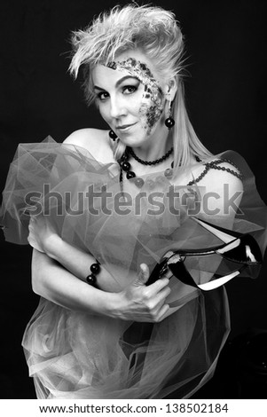 The Black-and-white image of the beautiful woman with a shoe in hands and with faceart on a black background
