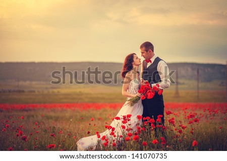 The bride and groom in a poppy field