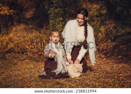 Mother and her daughter in vintage clothes with a cat
