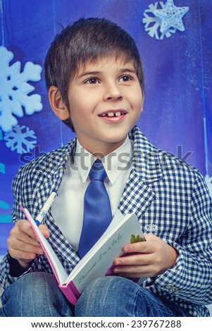 Winter Fashion. Portrait of adorable boy in jacket with book in studio.