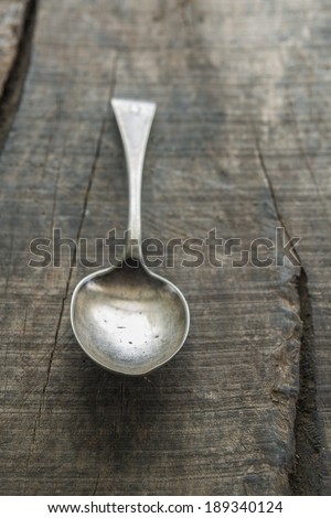 Silver serving spoon on old rustic wooden board
