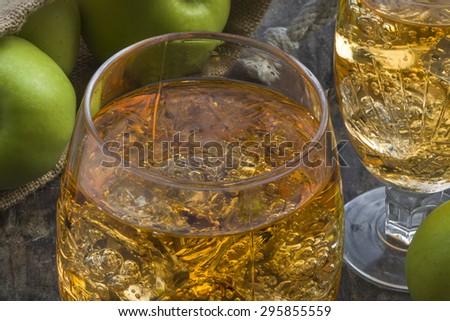 Refreshing apple cider with ice cubes and apples on wooden table