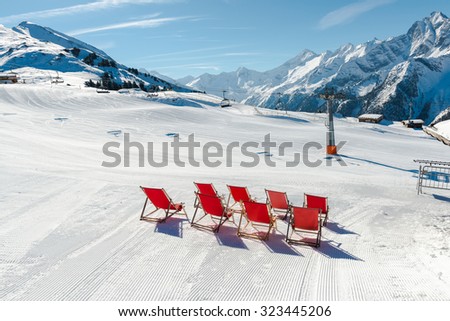 Empty red deck chairs on the snow in Mayrhofen ski resort, Austrian Alps