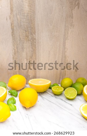 Fresh lime and lemon citrus fruits on marble table. Copy and paste your own text. Empty space next to yellow and green juicy fresh fruits on white bakground.