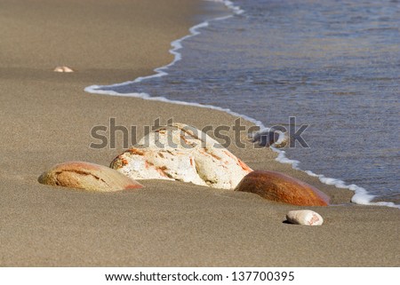 Water lapping on a sandy beach with some Stones, Milos island, Cyclades, Greece