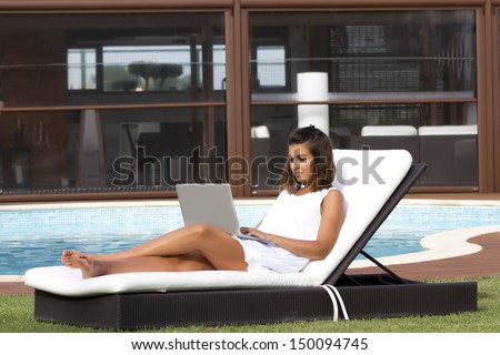 Sexy woman sunbathing and working on a chaise lounge near pool outdoors