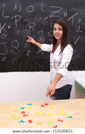 The teacher in the classroom is pointing the blackboard