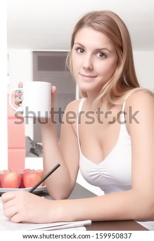 Young girl happy relaxed is drinking a cup of tea and reading a newspaper