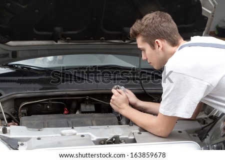 Portrait of happy mechanic repairing under car hood