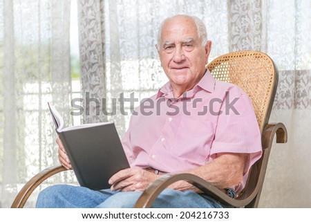 old man reading a book at home